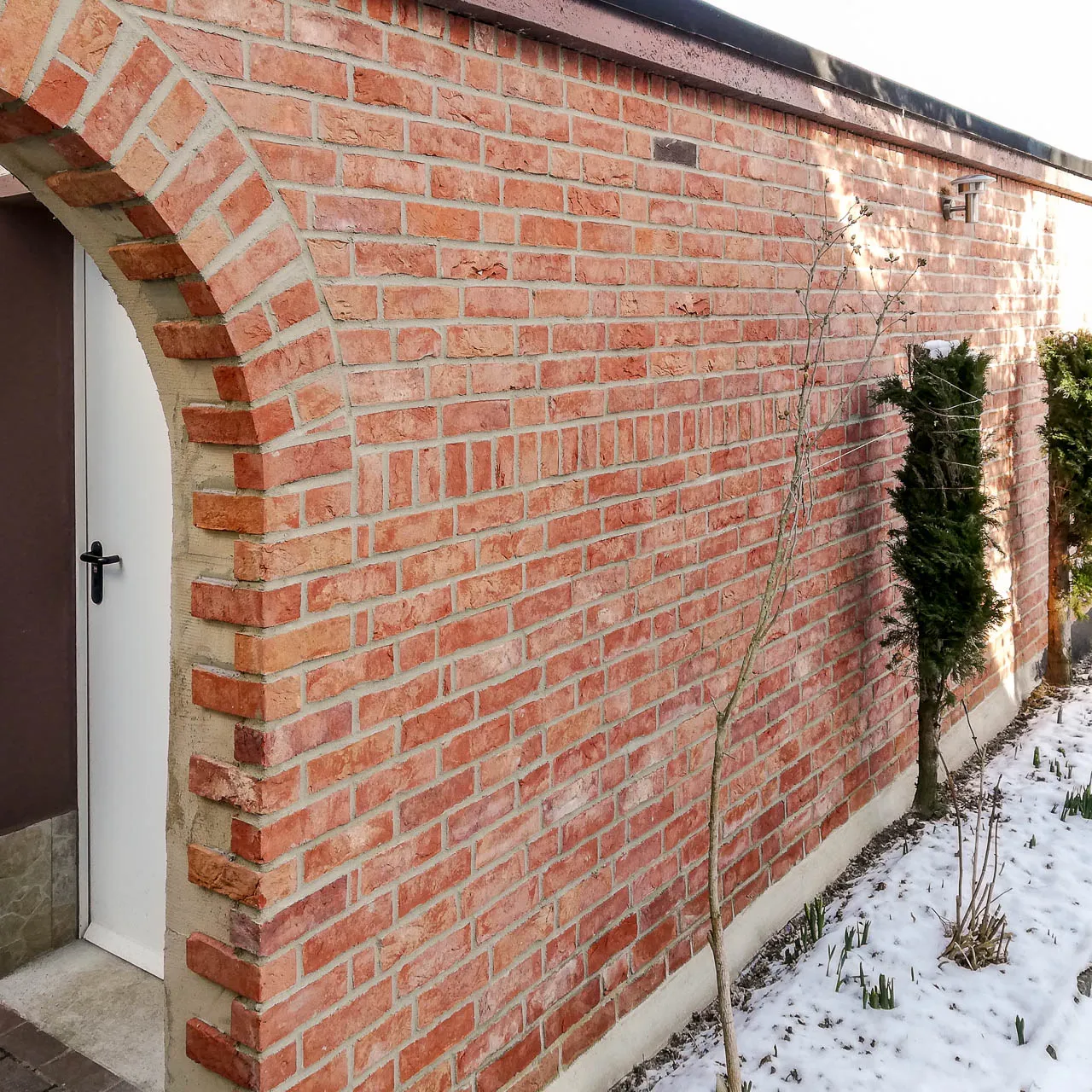 Eine kleine Außenfassade mit Rundung mit roten Klinkerriemchen der Sorte Exquisit rot. Mit der grauen Verfugung wirkt das Haus freundlich im klassischen Rot mit leicht gelblicher Besandung.