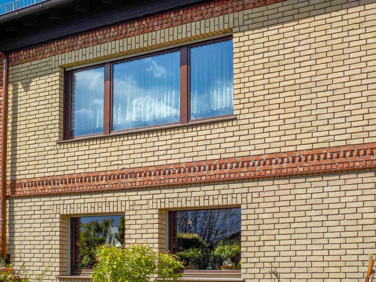 Hausfassade mit den Klinkerriemchen Sandgelb. Eine schöne gelbe Außenfassade. Es wurden mit roten Backsteinriemchen Akzente gesetzt. Ein insgesamt helle, freundliches und klassisches Haus.