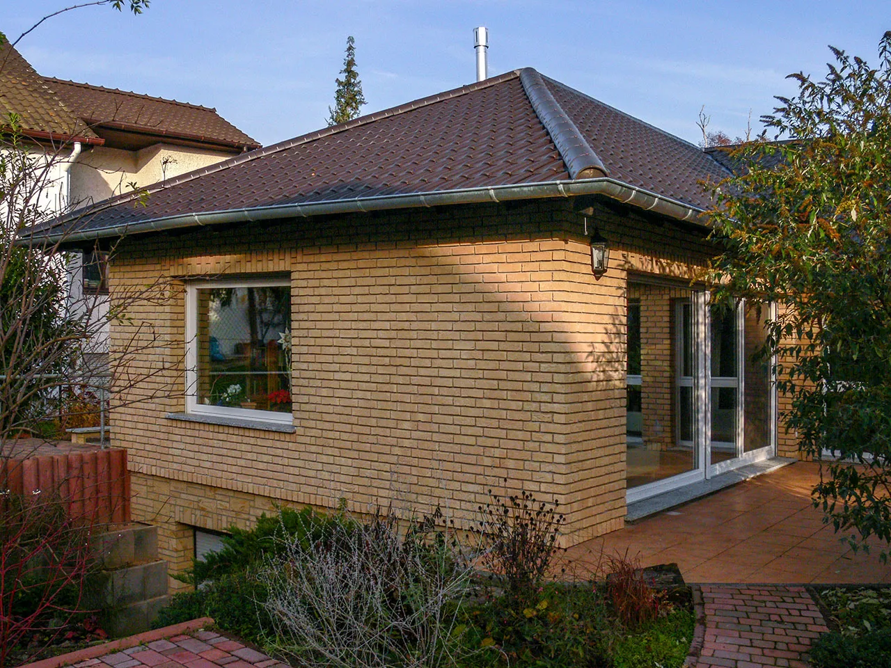 Hausfassade mit den Klinkerriemchen Sandgelb. Eine schöne gelbe Außenfassade. Es wurden mit roten Backsteinriemchen Akzente gesetzt. Ein insgesamt helle, freundliches und klassisches Haus.