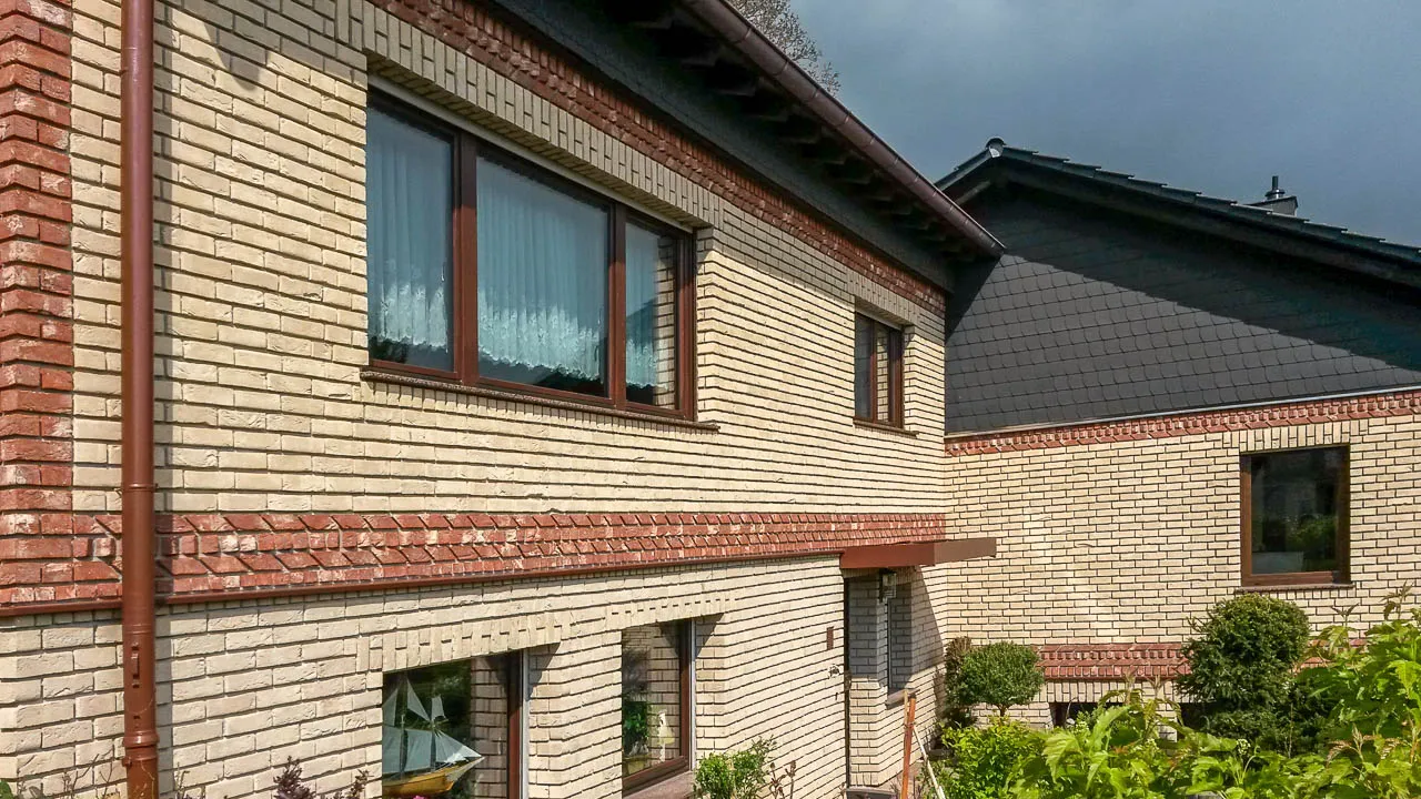 Hausfassade mit den Klinkerriemchen Sandgelb. Eine schöne gelbe Außenfassade. Es wurden mit roten Backsteinriemchen Akzente gesetzt. Ein insgesamt helle, freundliches und klassisches Haus.